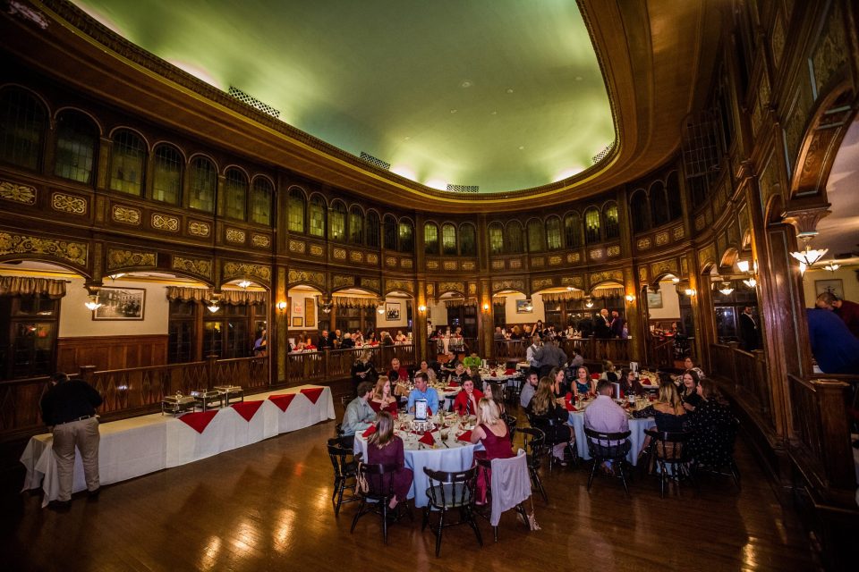 A large ornate hall features carved wood, arched windows and an illuminated dome.