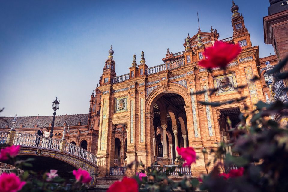 The ornate brick and tile façade features a large central arch, decorative towers and a gallery with a balustrade.
