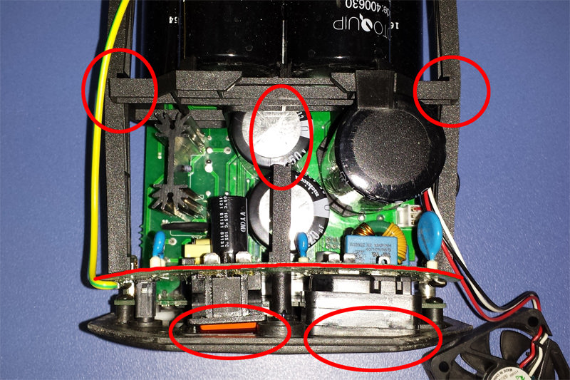Top-down photograph of an open electronic device with a green circuit board and several cylindrical capacitors.
