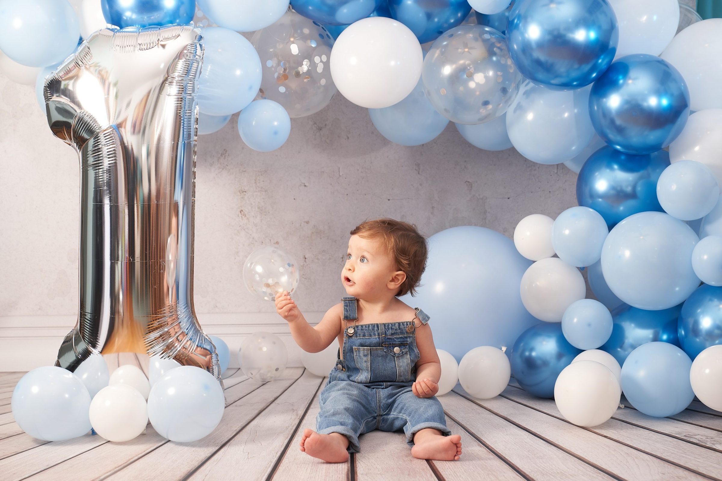 Fotografía de estudio con iluminación de flash en la que aparece un niño pequeño sentado sobre un suelo de madera.