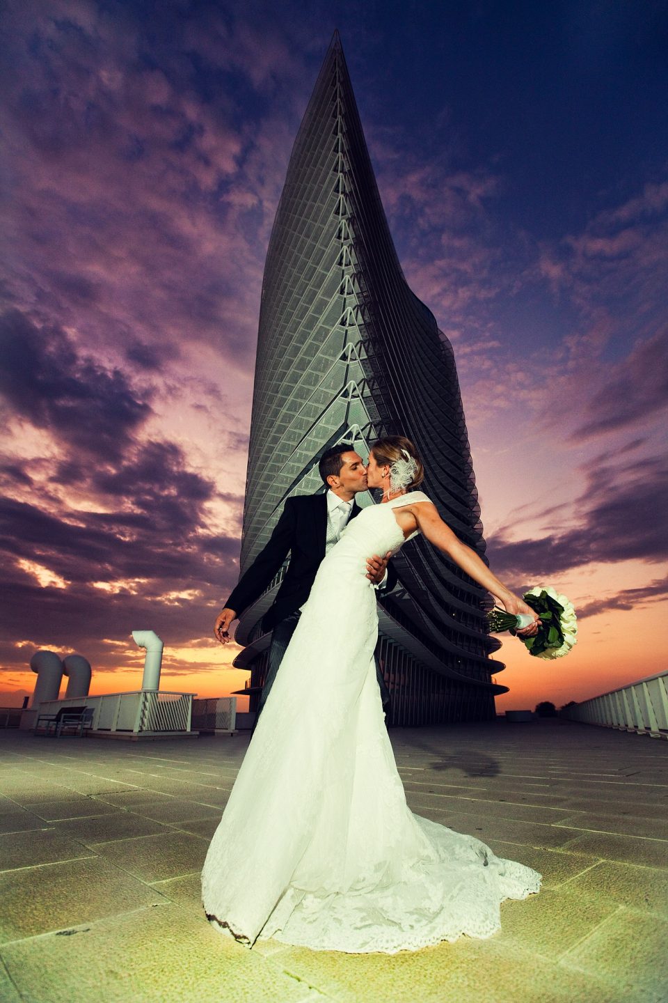 Fotografía de reportaje de boda tomada en 2011: una pareja se besa en una azotea al atardecer.