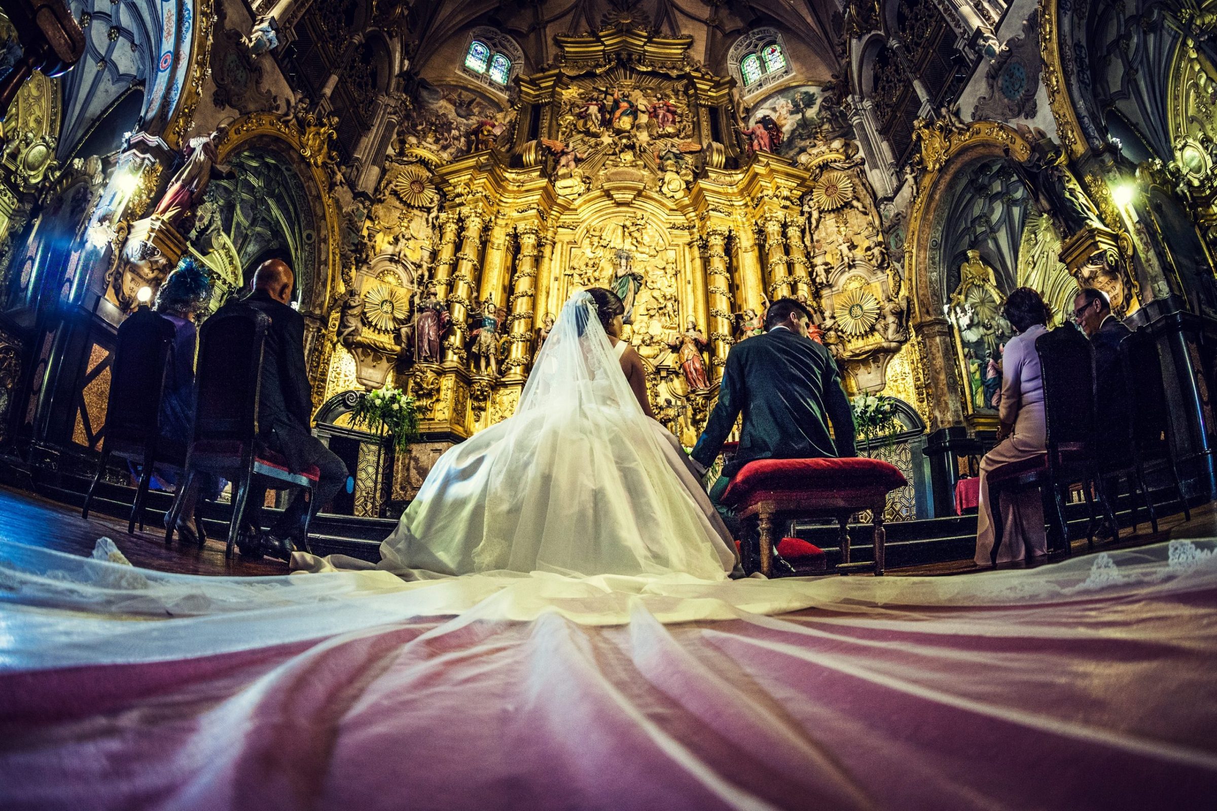 Fotografía de una ceremonia de boda en el interior de una iglesia ornamentada.
