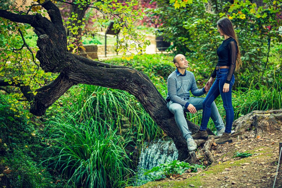 A couple are pictured beside a small stream in a green urban setting.