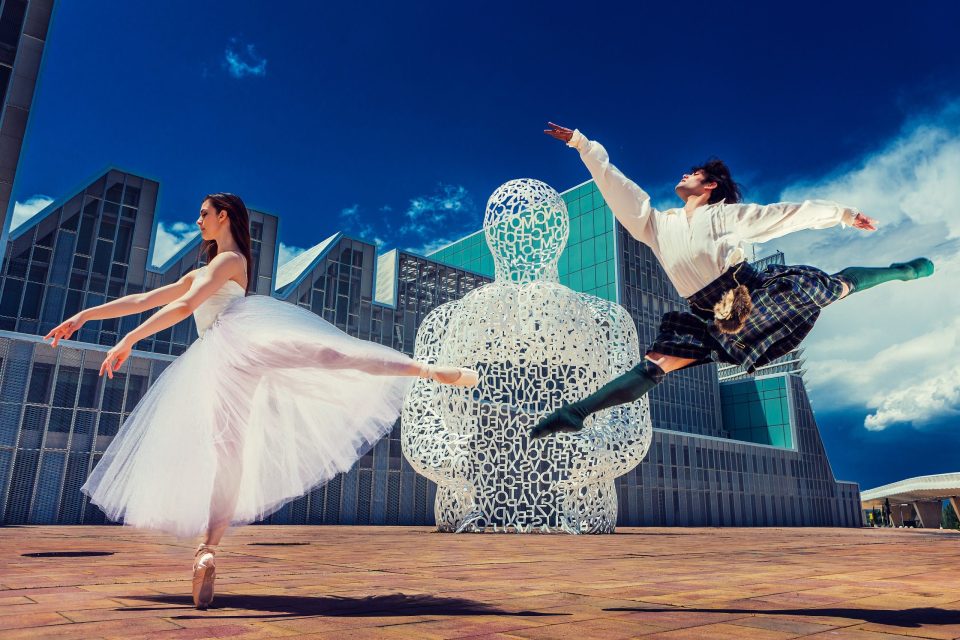 Fotografía editorial de glamour en una plaza urbana, con dos modelos en movimiento.