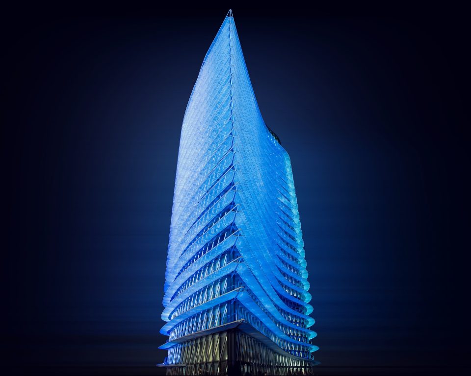 A very tall modern building is photographed at night from a low angle.