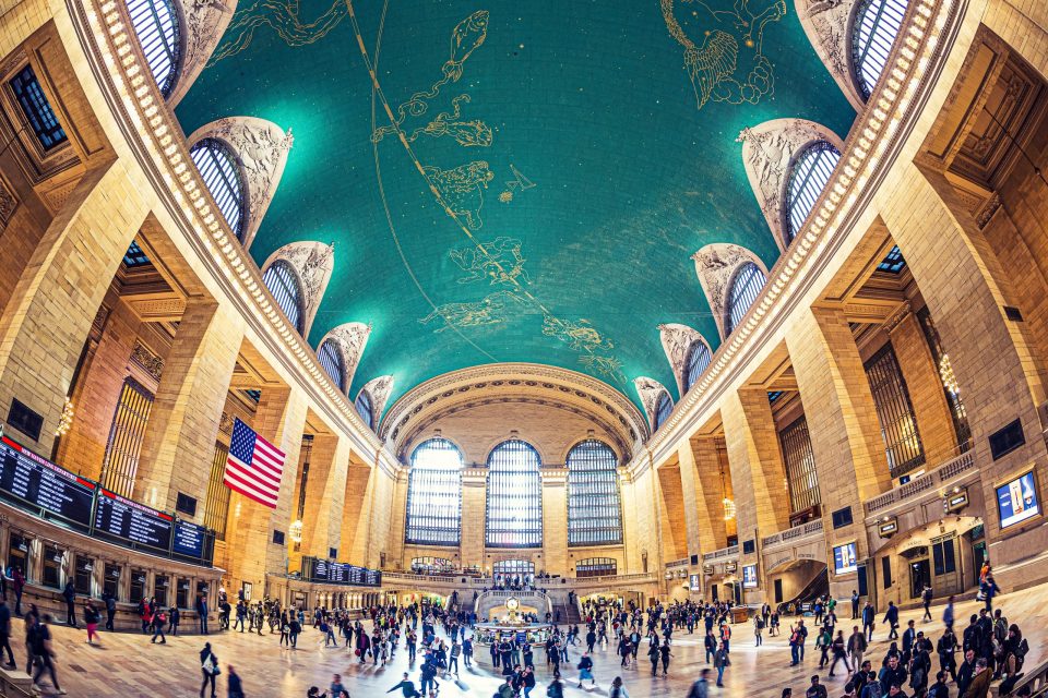 This is a spacious, symmetrical interior of a grand station, with monumental stone architecture and large arched windows.