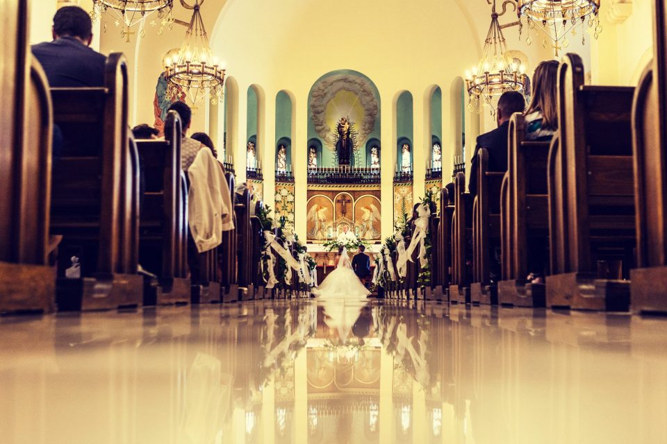 Interior de una iglesia decorada para una ceremonia de boda, fotografiado desde el pasillo central a ras de suelo.