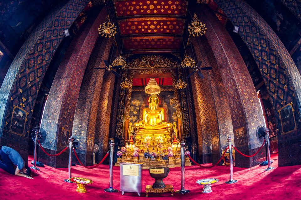 The ornate interior of a temple has walls and a ceiling decorated with floral and gold motifs.