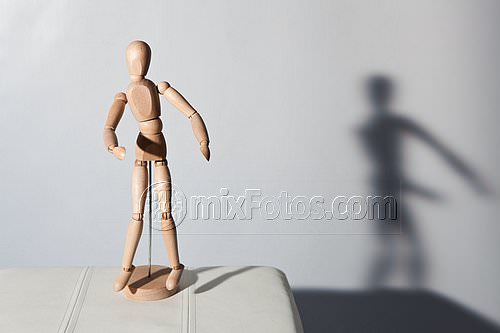 A wooden articulated mannequin is on the open pages of a book, lit from the left.