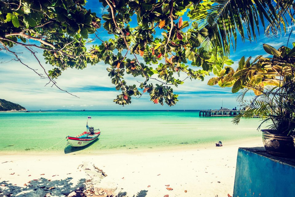 Tropical beach landscape with white sand and calm turquoise waters.