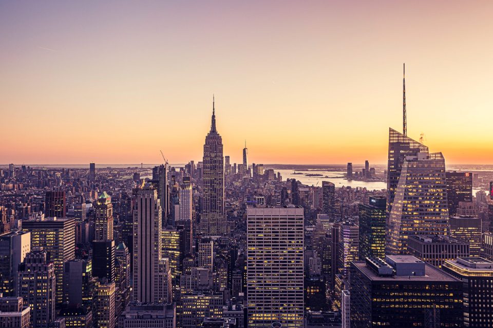 An urban panorama at sunset with the Empire State Building in the centre.