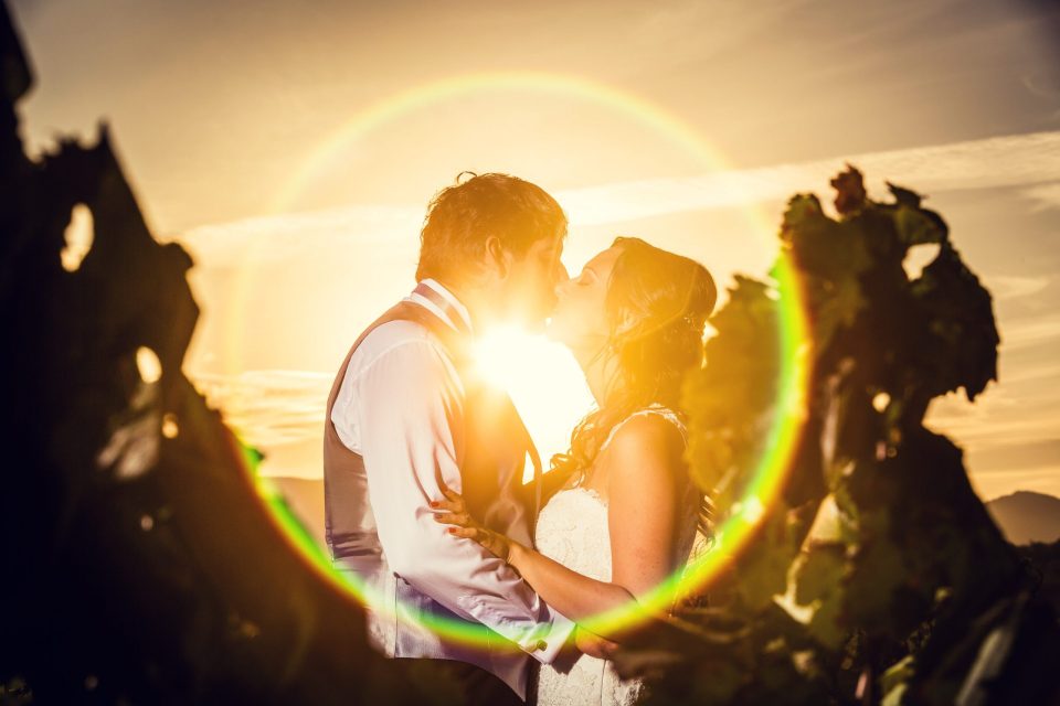 Pareja de novios besándose al atardecer en un entorno de campo, entre formaciones rocosas.