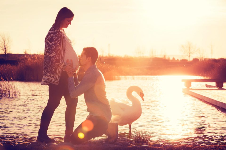 Pareja junto a un estanque al atardecer.