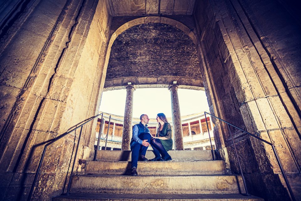 Pareja sentada y conversando en unas escaleras de piedra.
