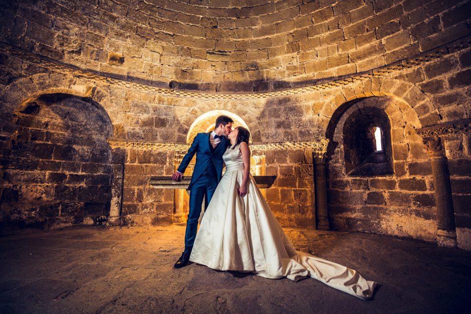 A couple dressed for a wedding, one in a dark suit and the other in a white wedding dress.