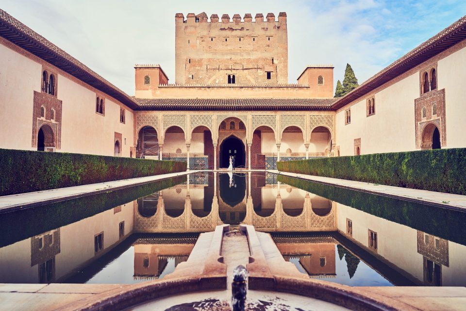 Patio histórico de arquitectura islámica con arcos decorados, muros encalados.