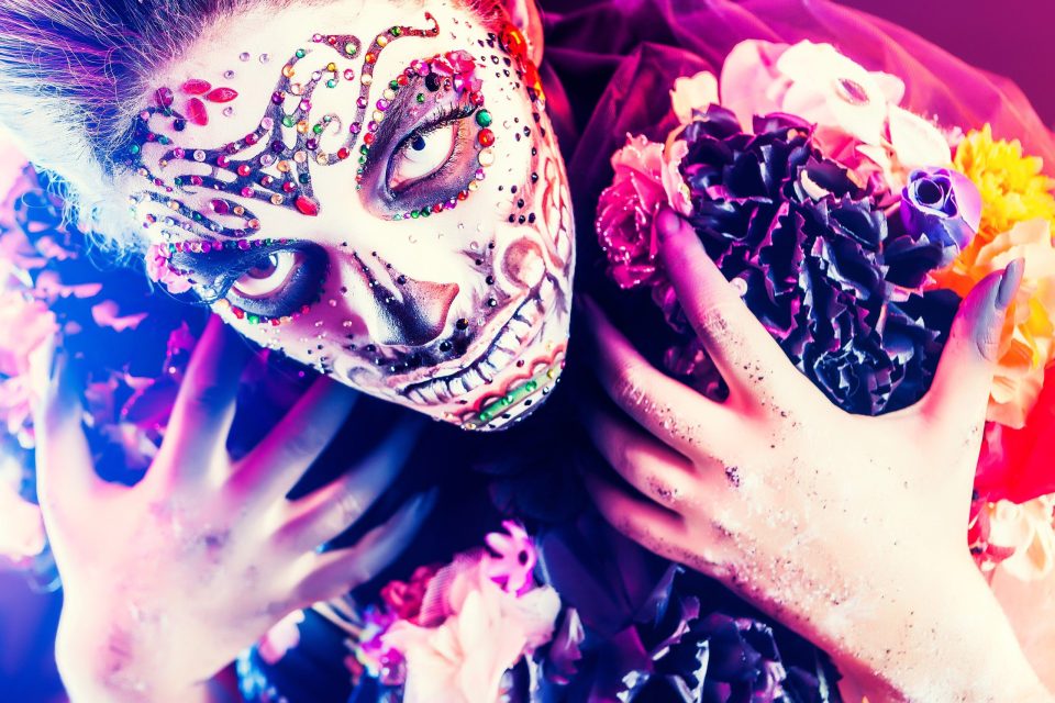 Primer plano editorial de una modelo con maquillaje artístico de fantasía inspirado en una calavera.