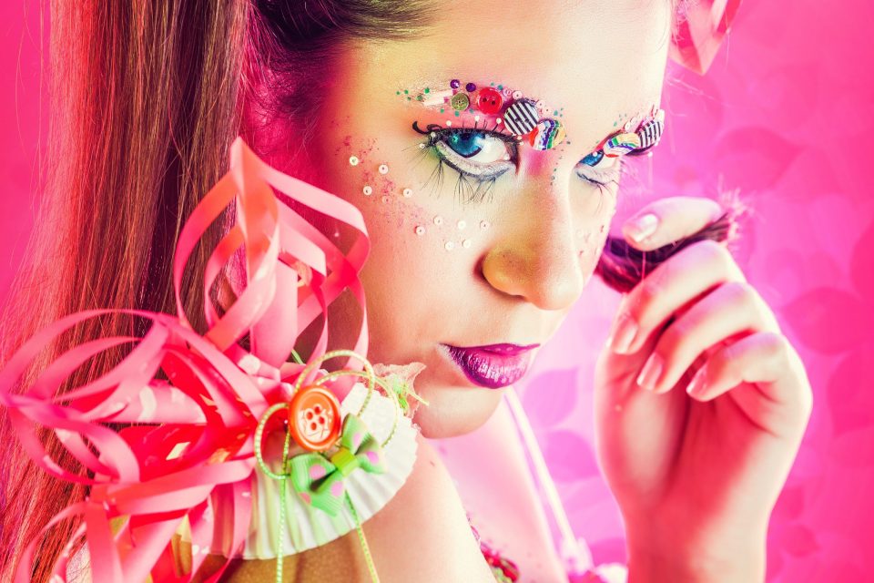 Primer plano editorial de una modelo con maquillaje artístico y labios magenta.