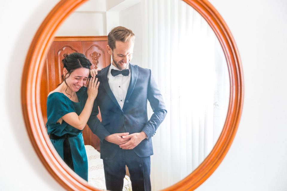 Reflejo de una pareja en un gran espejo ovalado dentro de una casa.