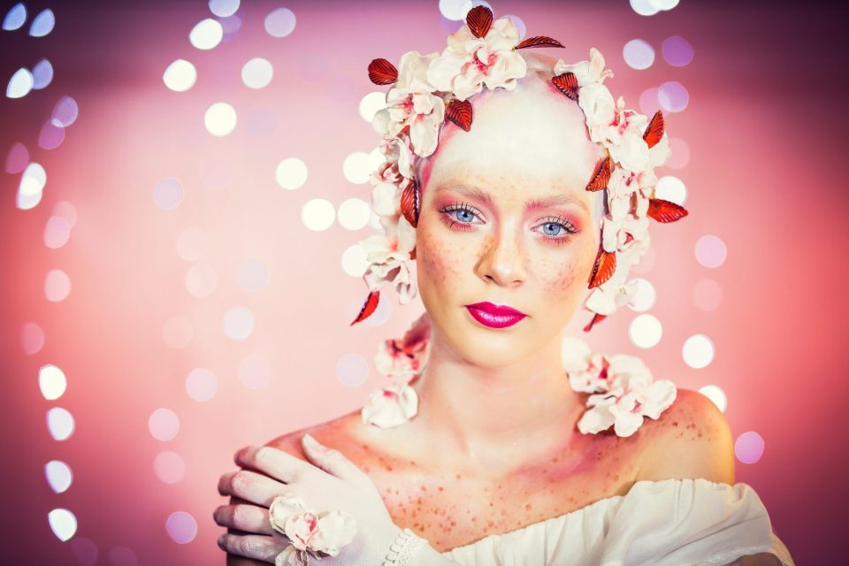 Retrato de belleza editorial en estudio: una modelo mira a cámara con maquillaje en tonos rosados y labios fucsias.