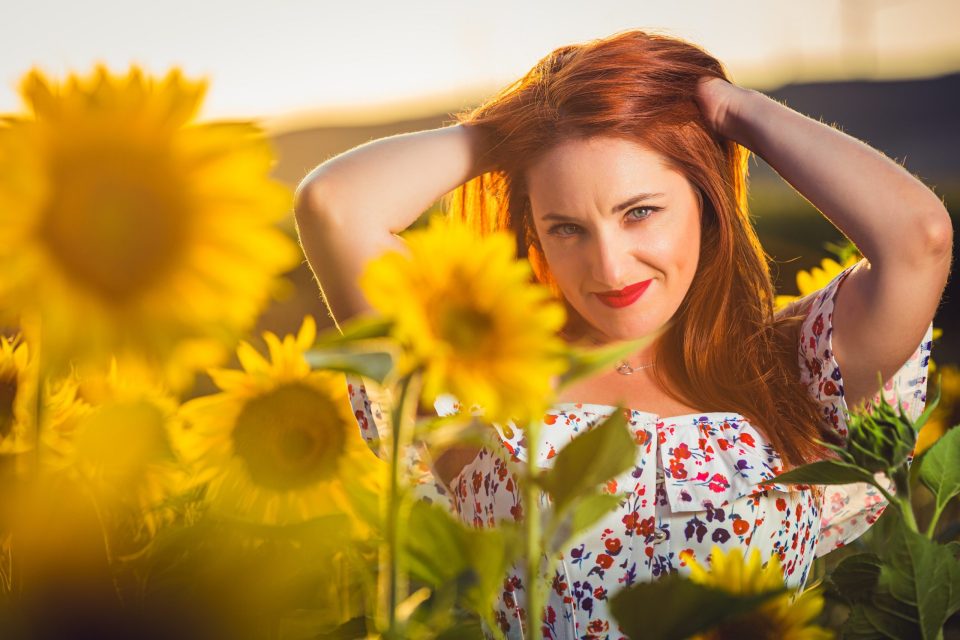 Portrait of a red-haired woman among sunflowers.