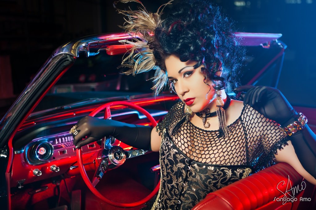 A woman sits inside a car with one hand on the steering wheel.