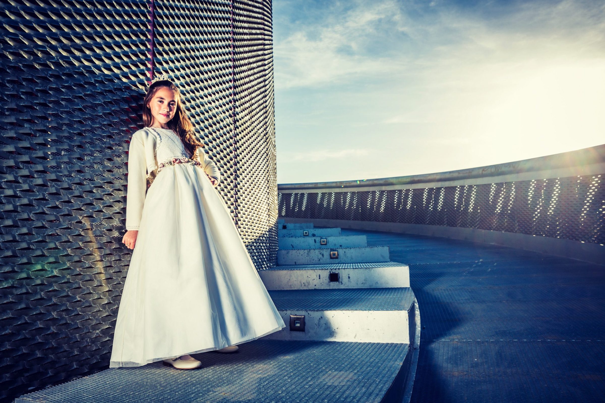 Retrato de una niña con vestido blanco largo y zapatos claros.