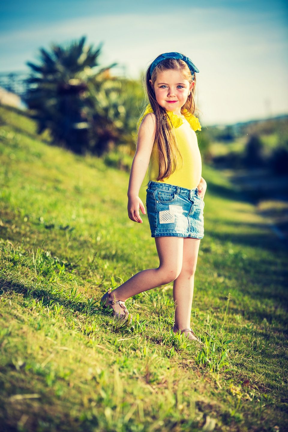 Retrato de una niña de pie sobre una zona de césped en un parque.