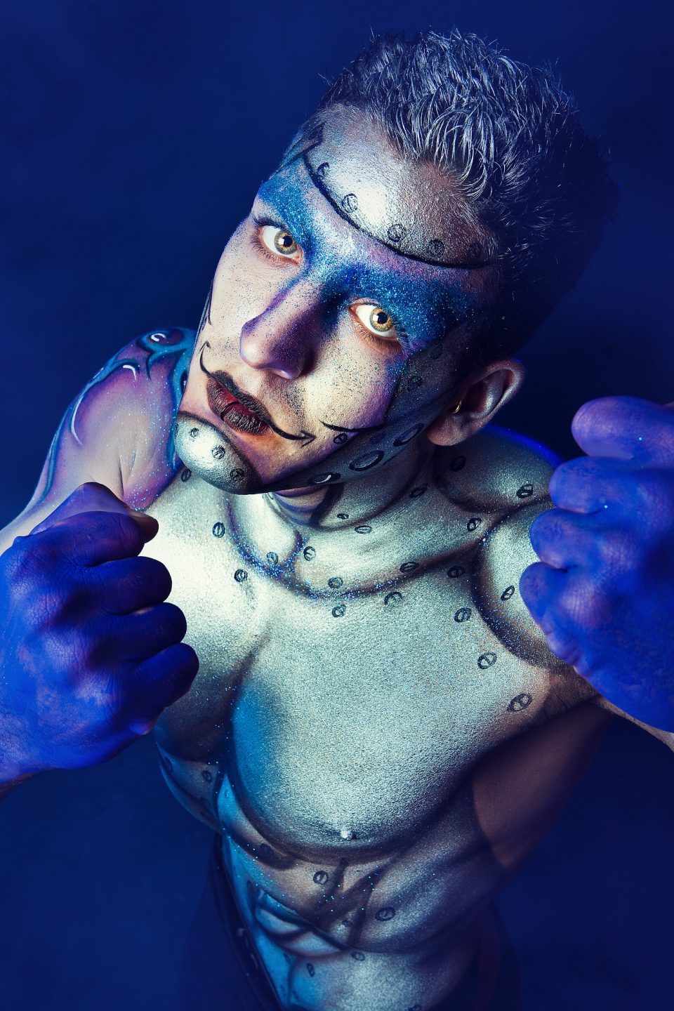 Retrato editorial de fantasía en estudio, iluminado con flash y dominado por tonos azules y violetas.