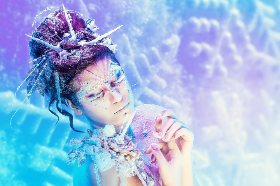 Retrato editorial de fantasía en estudio: una modelo aparece con maquillaje artístico brillante.