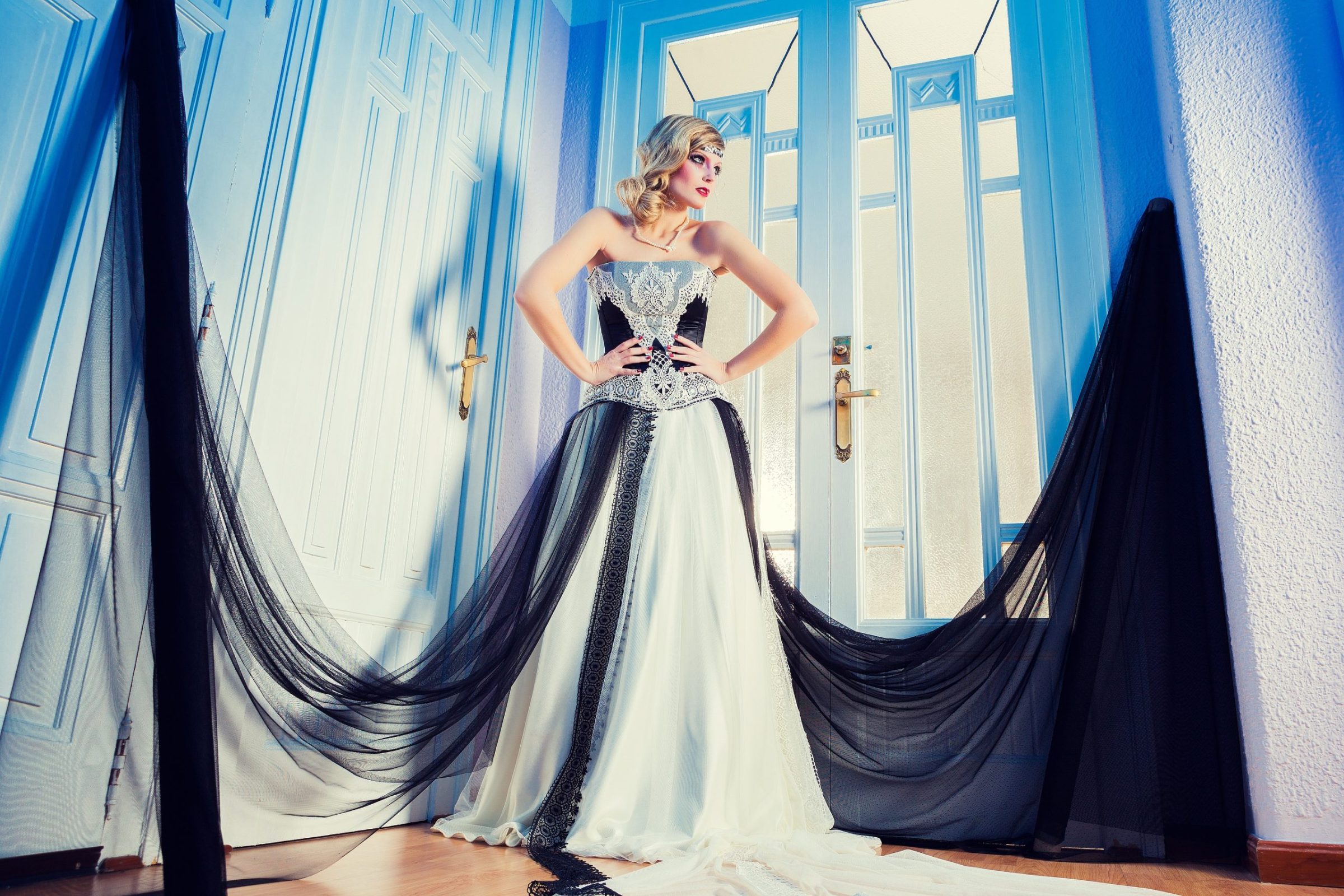 Retrato editorial de una modelo rubia en el interior de un estudio, frente a unas puertas blancas con detalles azules.