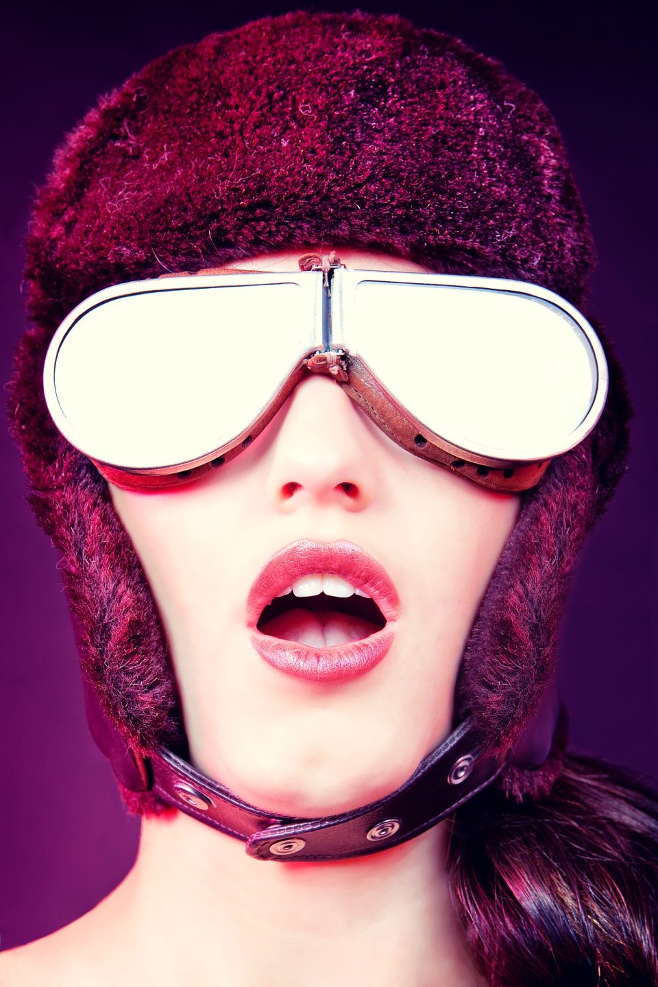 Retrato editorial en primer plano de una modelo con gafas grandes de montura plateada y lentes blancas reflectantes.