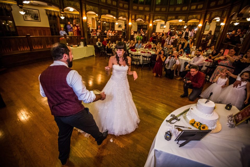 A couple dance in the centre of a wedding reception room with a wooden floor and classic-style décor.