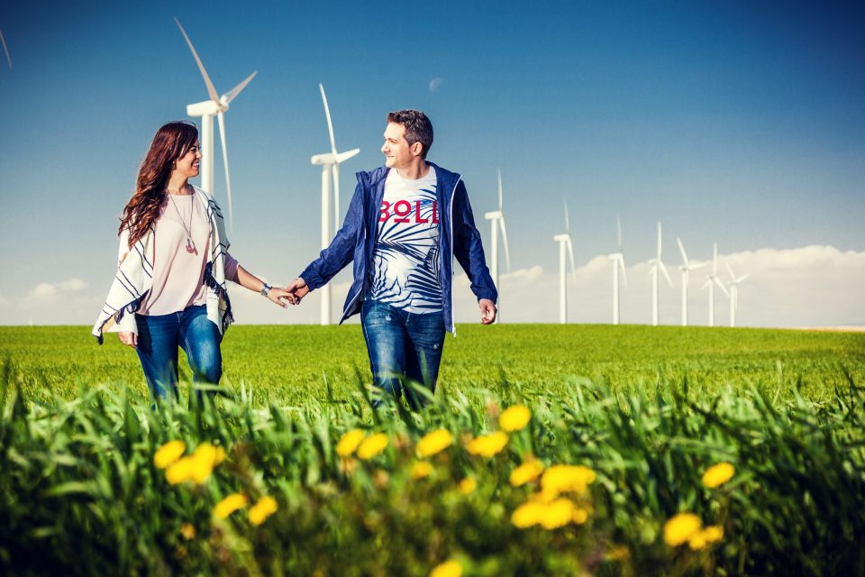 Una pareja camina de la mano por un campo verde con flores amarillas.