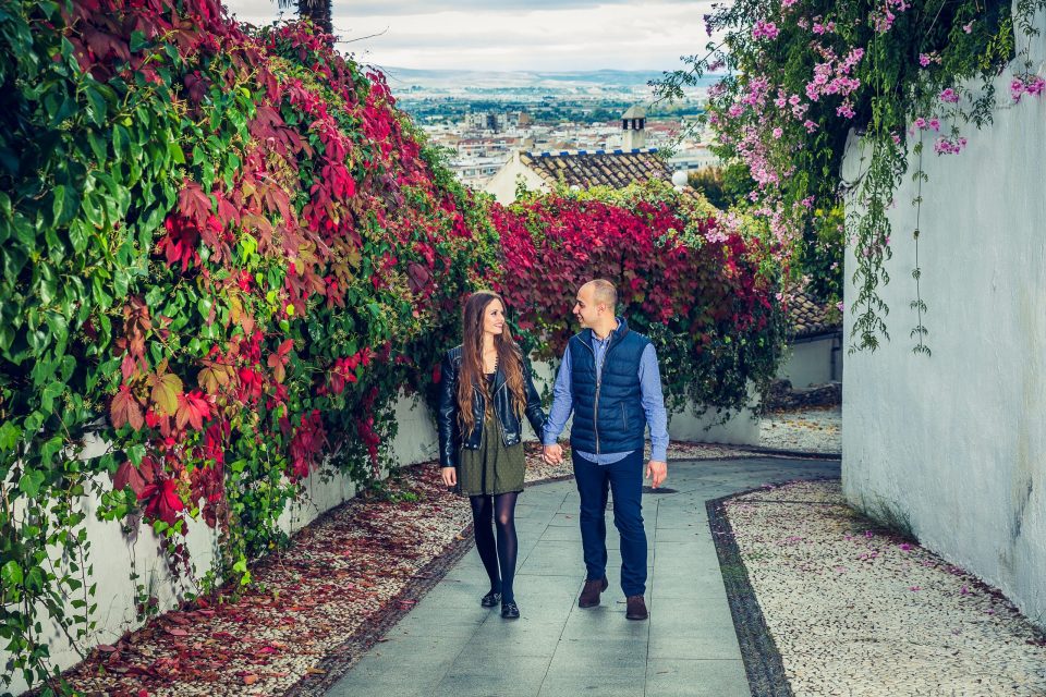 A couple walk hand in hand along a cobbled path.