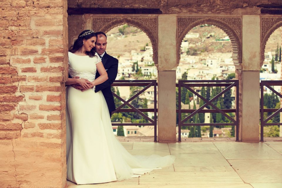 Una pareja de novios posa abrazada en una galería de un monumento histórico.