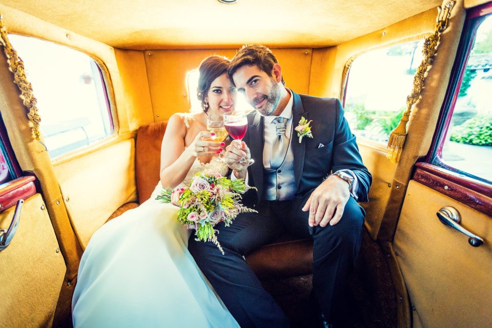 Una pareja de novios posa en el interior de un coche clásico.