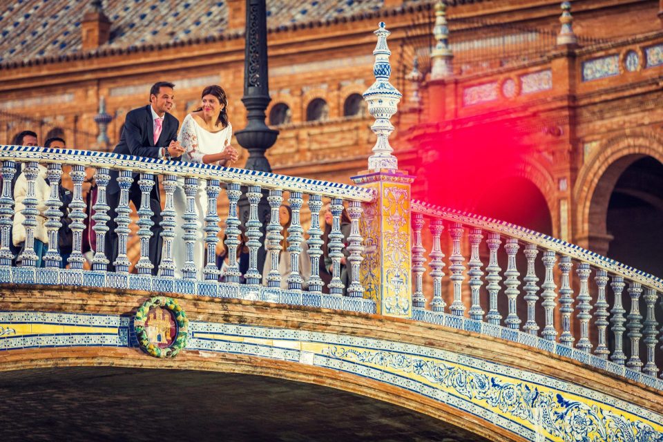 A bride and groom pose on a bridge adorned with an elaborate blue-and-white ceramic balustrade.