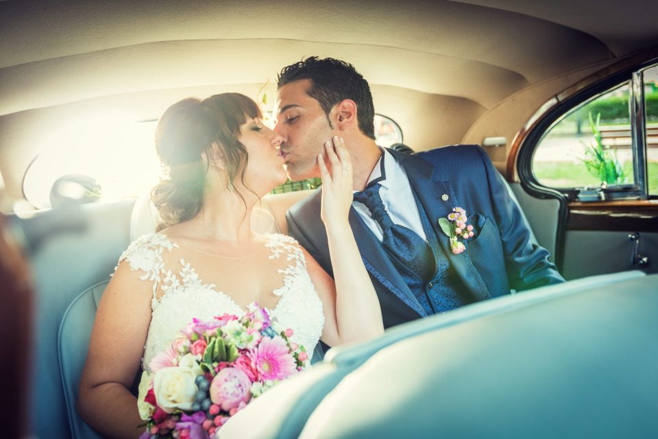 Una pareja de novios se besa en el interior de un coche.