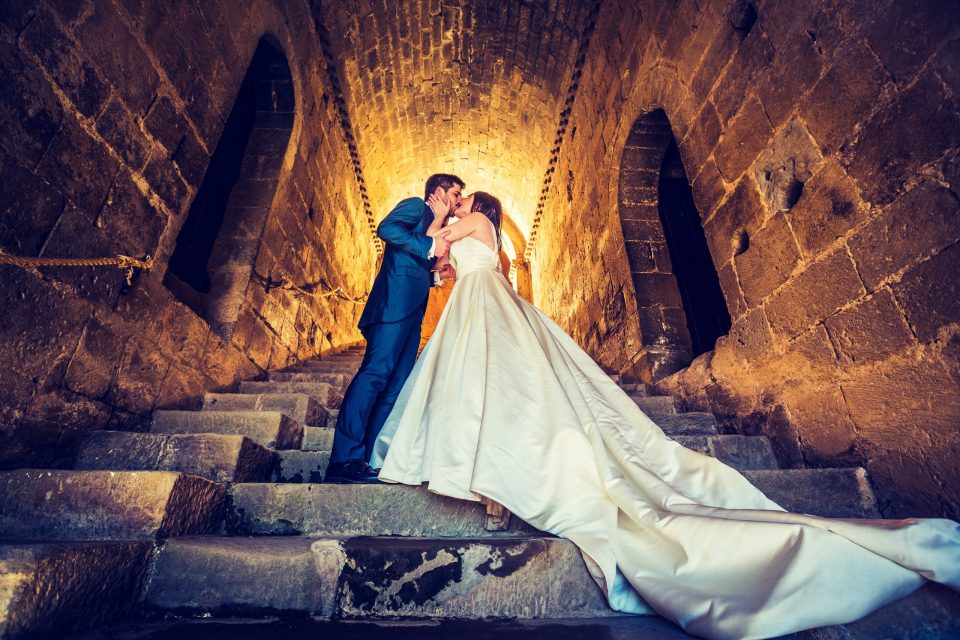 Una pareja de novios se besa en unas escaleras de piedra del interior de una iglesia.