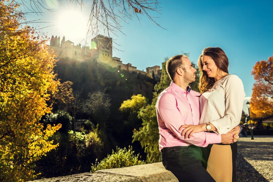 A couple pose embracing outdoors.