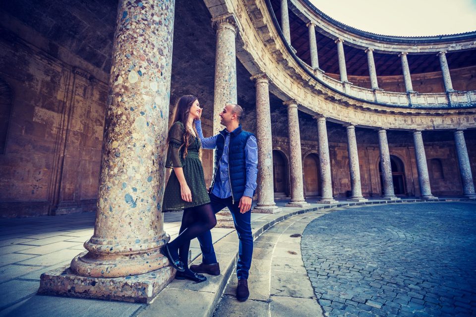 Fotografía de preboda en un patio histórico con columnas de piedra y una galería semicircular.