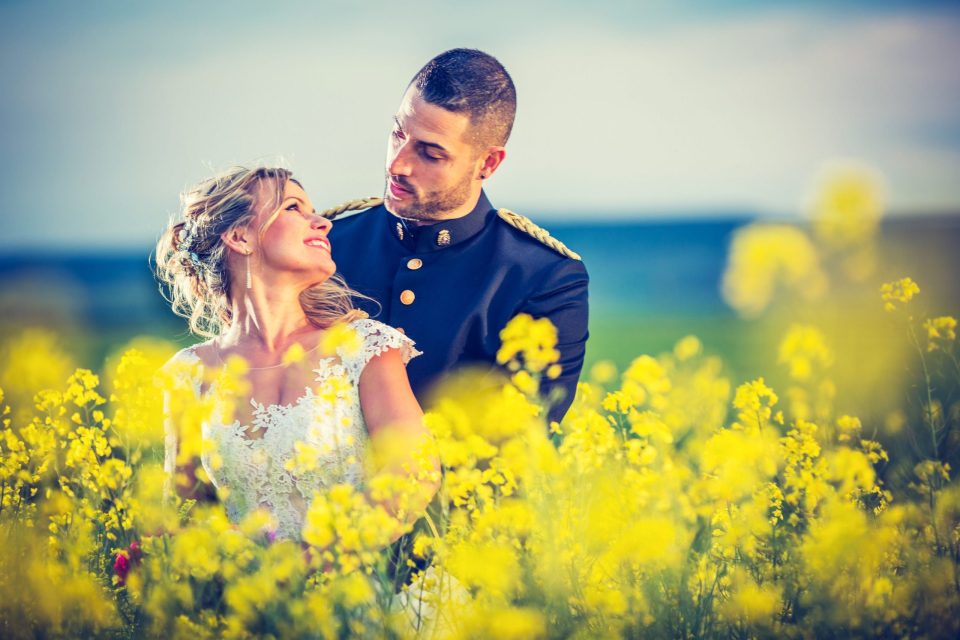 Una pareja posa en un campo de flores amarillas.