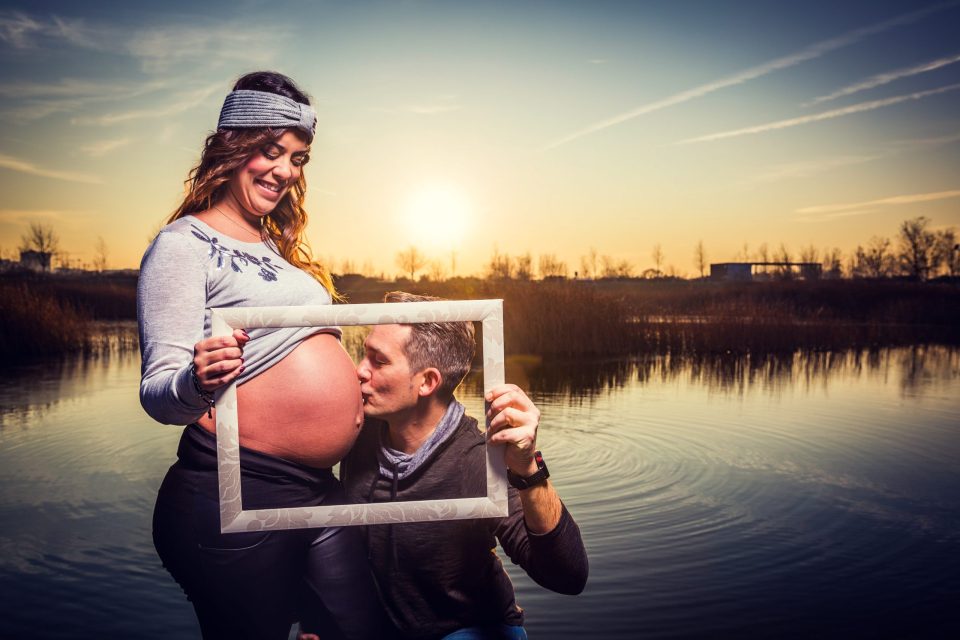 Una pareja posa junto a un estanque al atardecer.