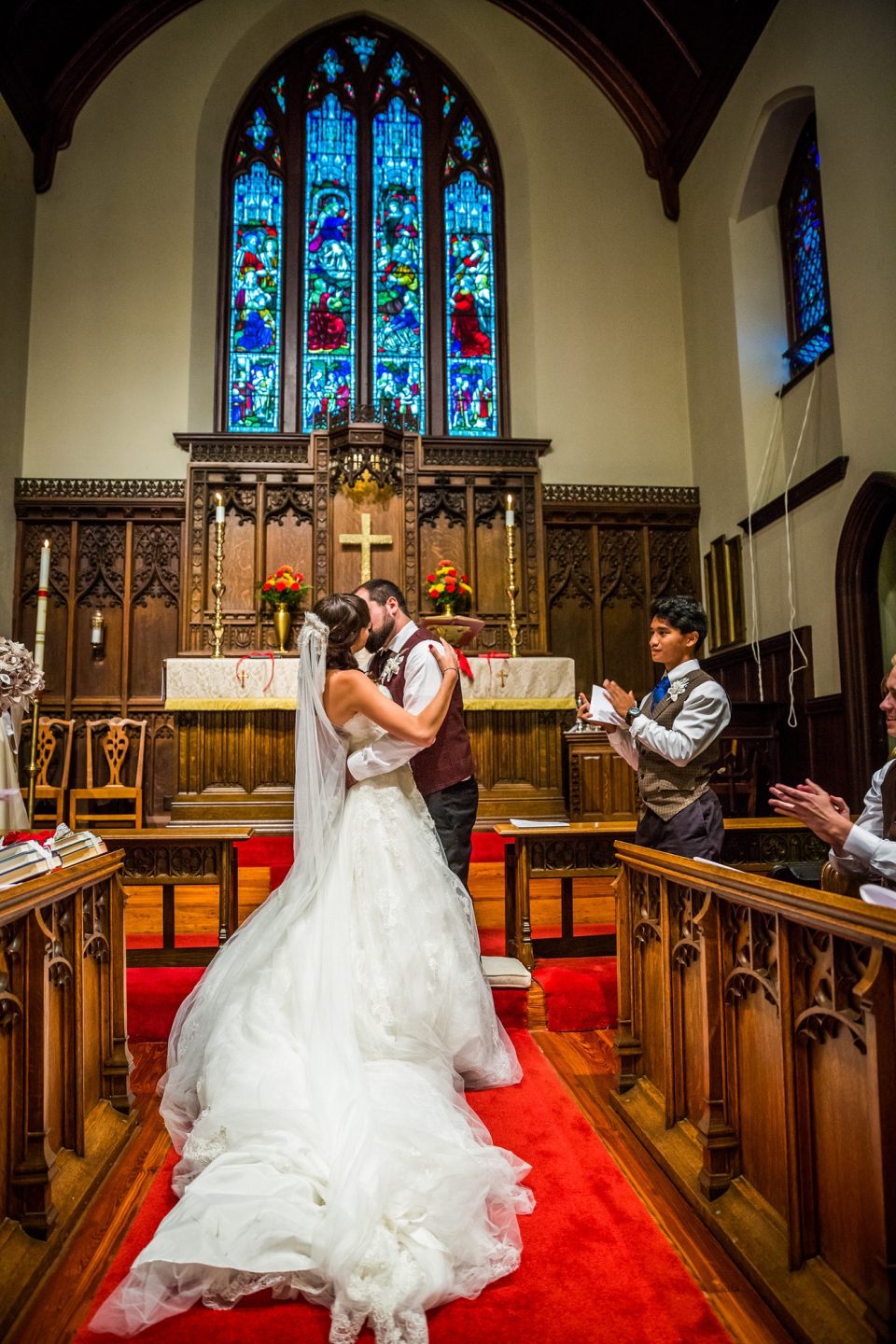 A couple kiss in front of a church altar during a wedding.