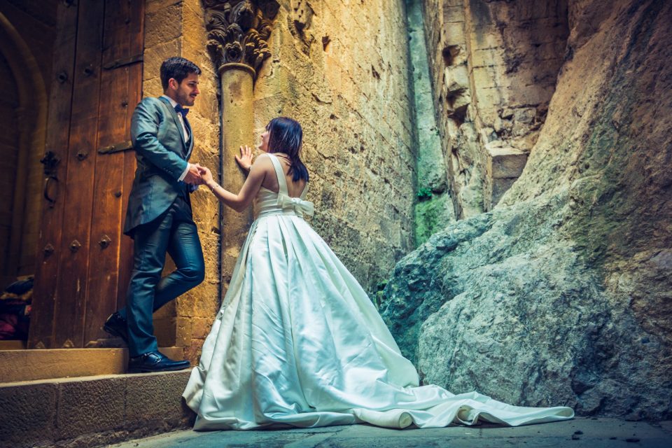 A couple dressed for a wedding pose in an old stone entrance.