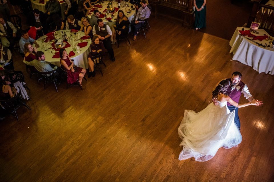 An elevated view of a newlywed couple dancing on a wooden dance floor.
