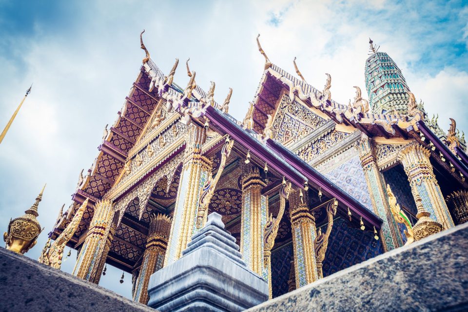 Low-angle view of a Thai-style temple with ornate roofs.