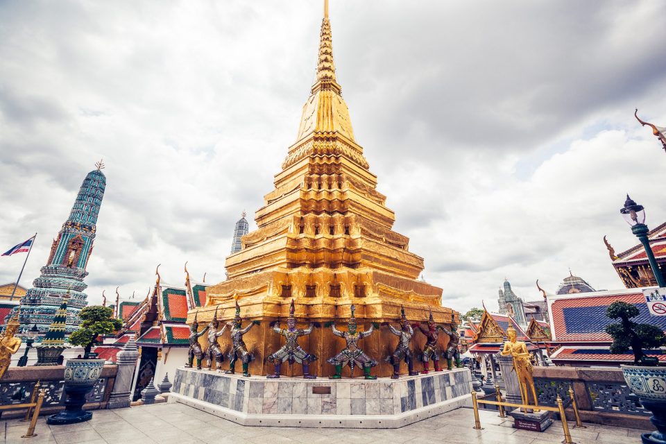 A Buddhist architectural complex with a large ornate golden stupa in the centre is seen from the front.