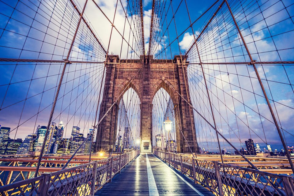 A front view of an urban suspension bridge at dusk.